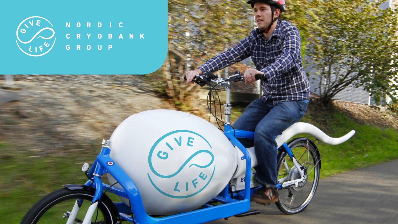A man riding a bike with a large white ball as part of a brand refresh.
