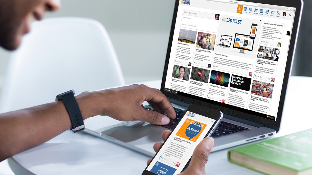 A man is using a BrandOS laptop and a cell phone.