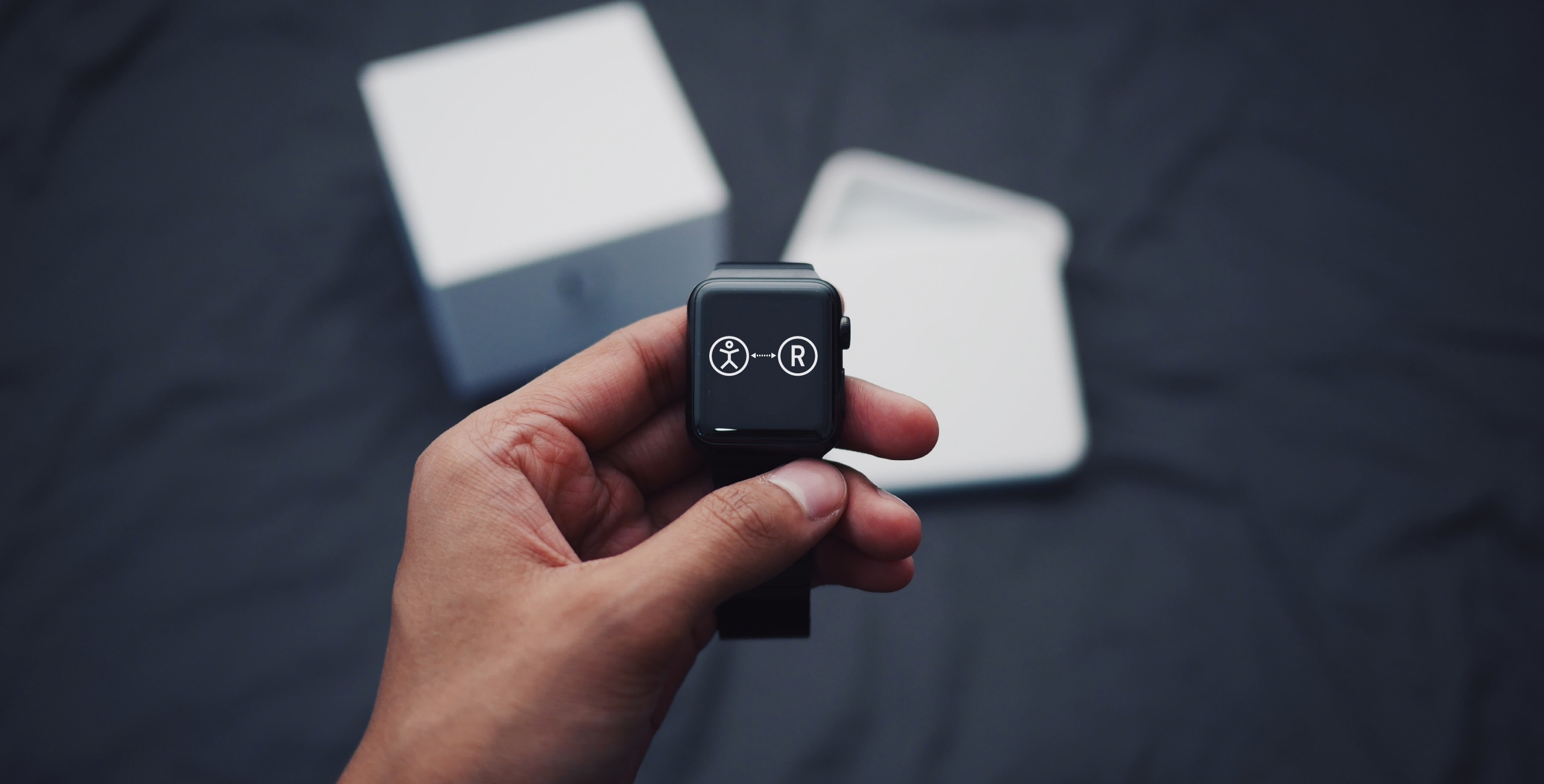 A person holding an apple watch in front of a box.