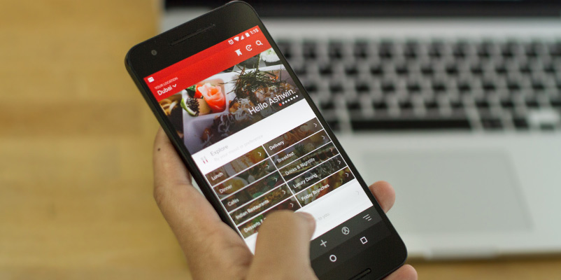 A person holding a phone with a video on it comparing food delivery brands head to head.