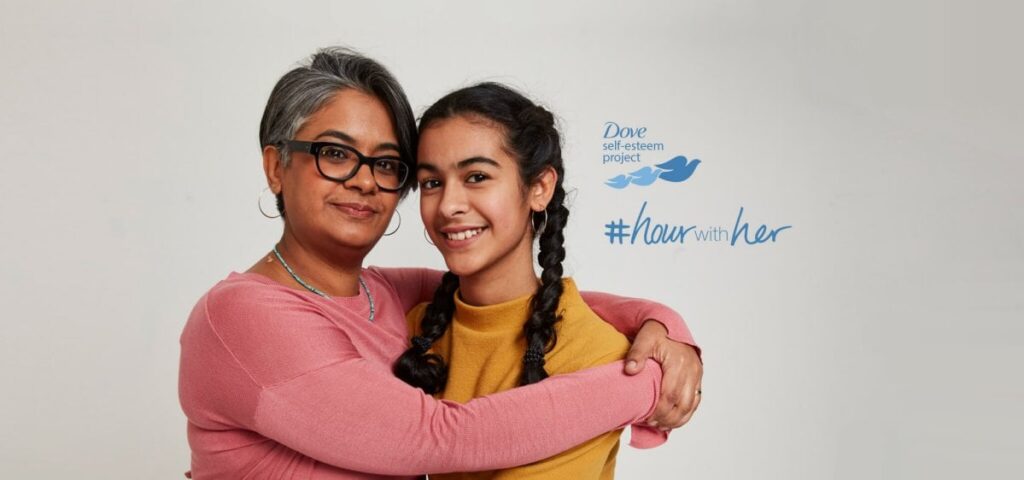 A mother and daughter hugging in front of a white background.