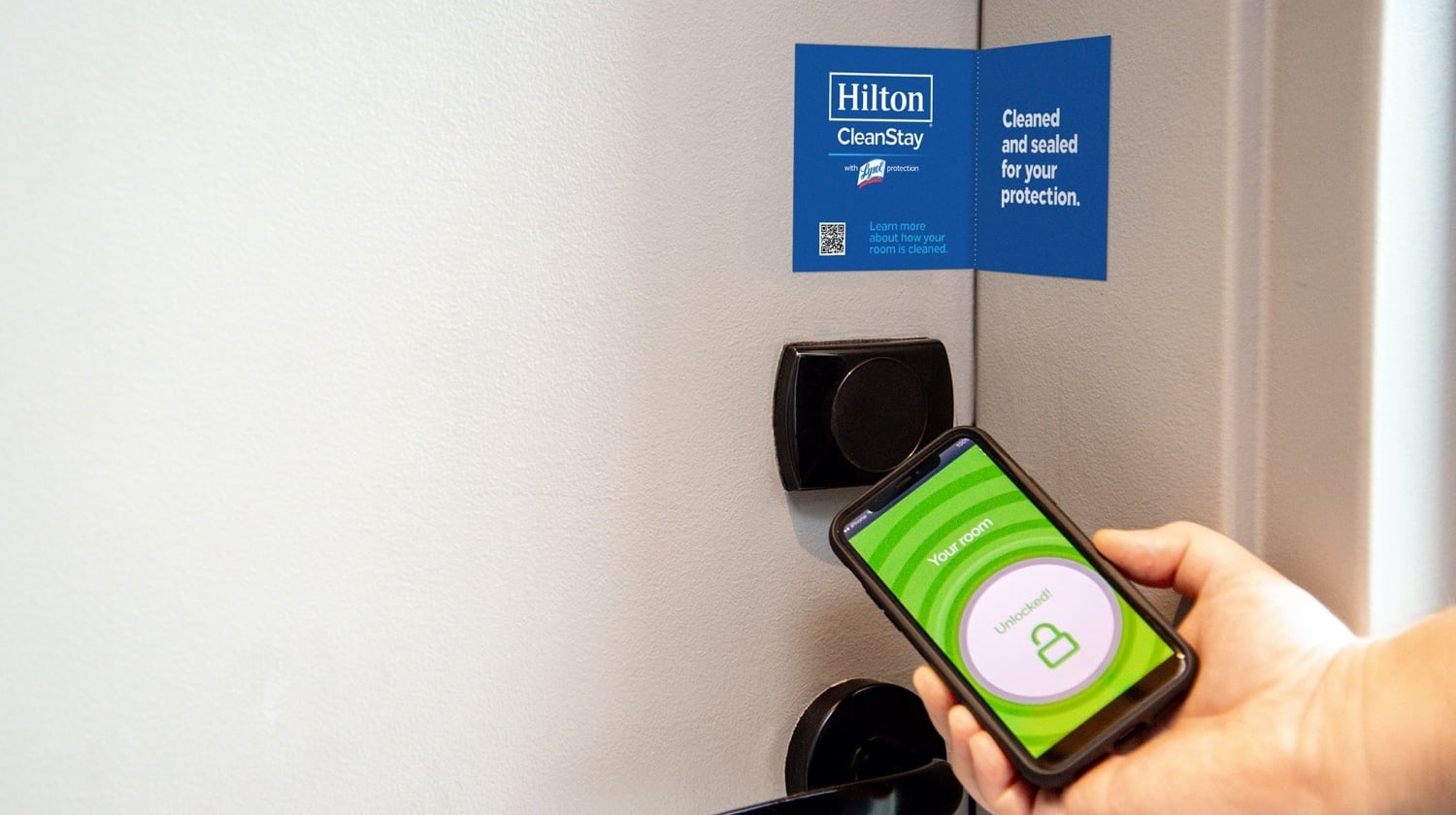 A person holding a cell phone next to a door.