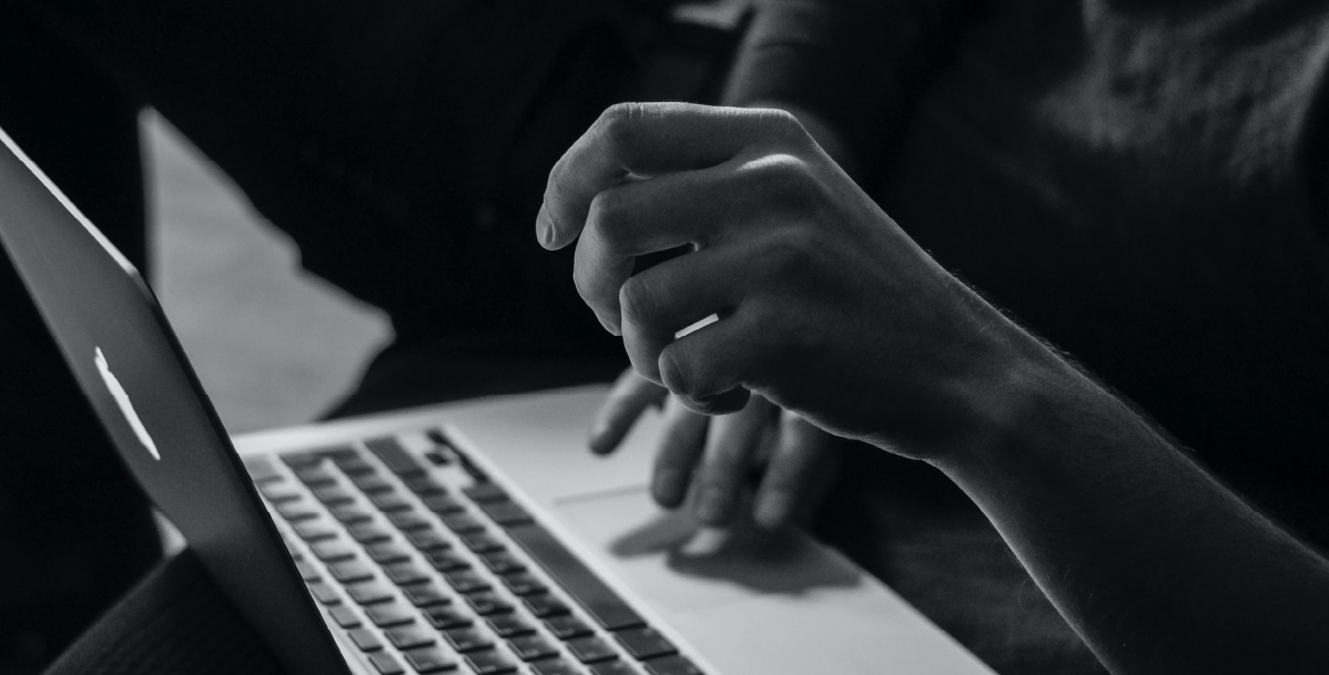 A black and white photo of a person using a laptop.