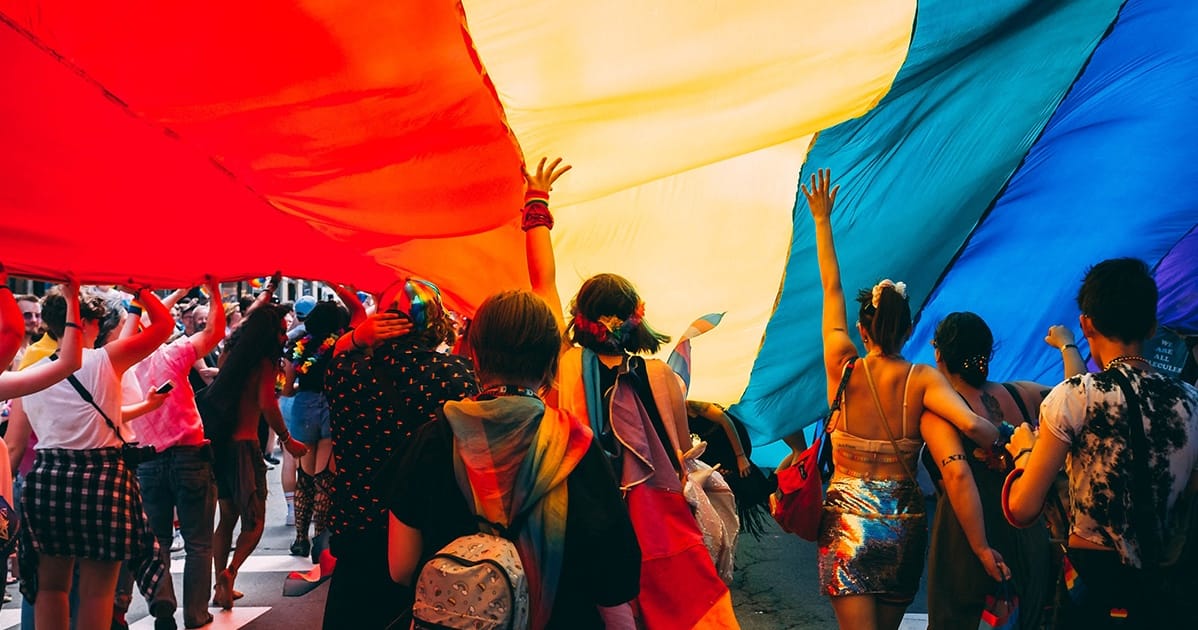 A group of people holding a rainbow flag.