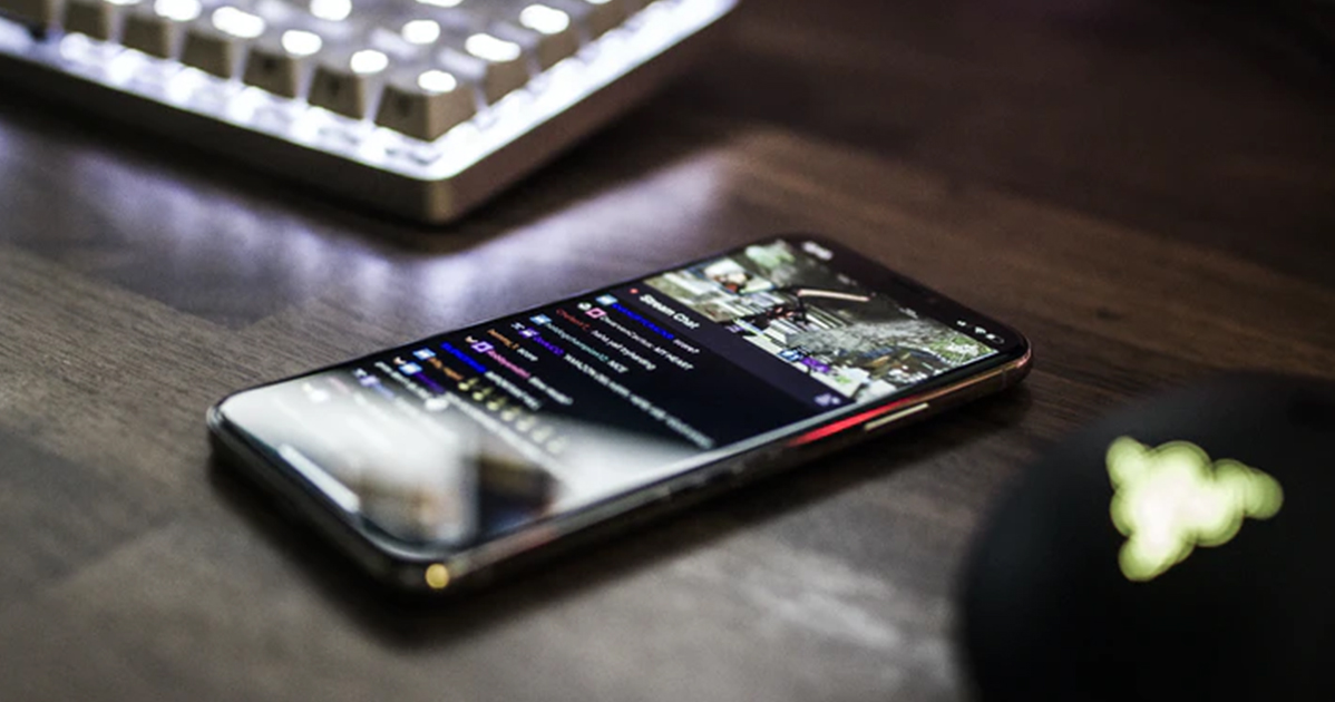 A smartphone is sitting on a table next to a keyboard.
