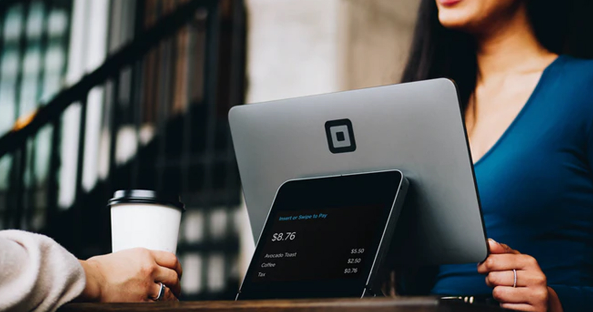 A woman is sitting at a table with a laptop and a cup of coffee.