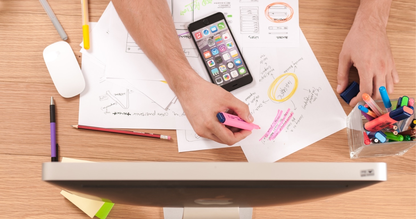 A person conducting quantitative and qualitative research on a computer with pens and papers.