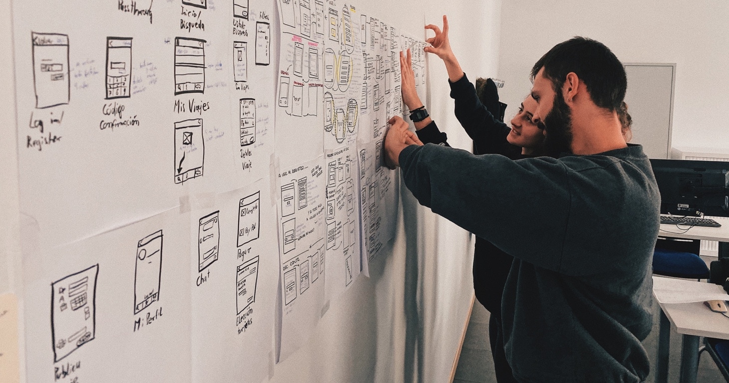 Two people collaborating on a whiteboard to enhance communication and qualitative research in an office setting.