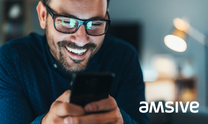 A man is smiling while looking at his phone.