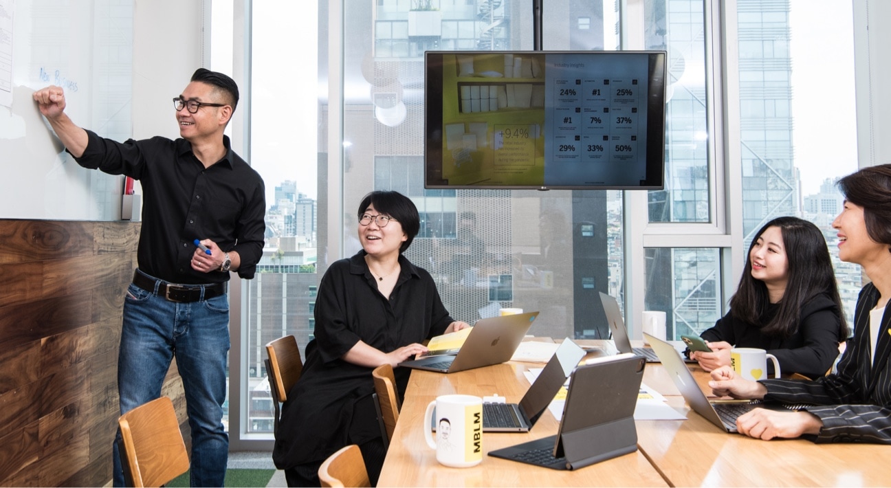 A group of people sitting around a table in a meeting room.