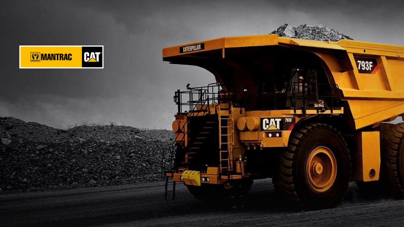 a large yellow dump Mantrac truck driving down a dirt road