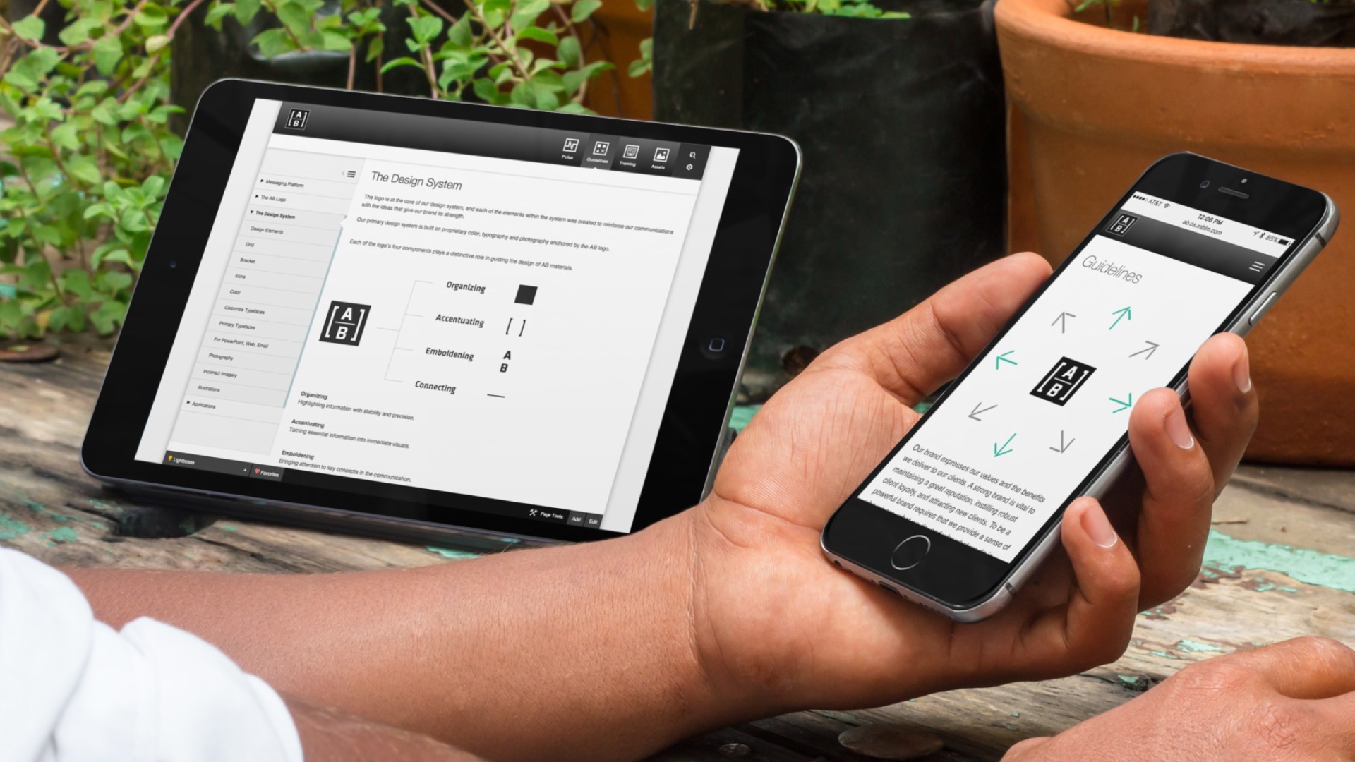 a man with a mobile phone and a tablet displaying the brand management system developed with BrandOS for AB (AllianceBernstein)