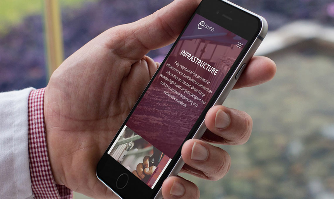A man with a mobile phone in his hands with the website designed for Elwan Group