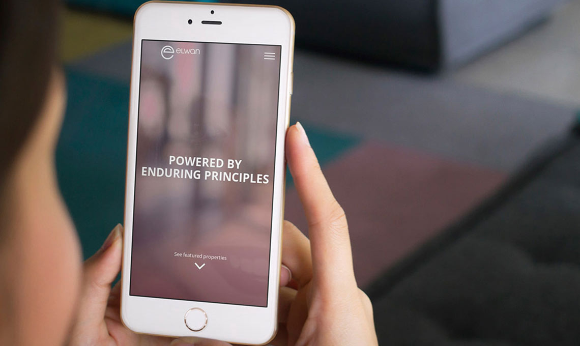 A woman with a tablet in her hands with the website designed for Elwan Group