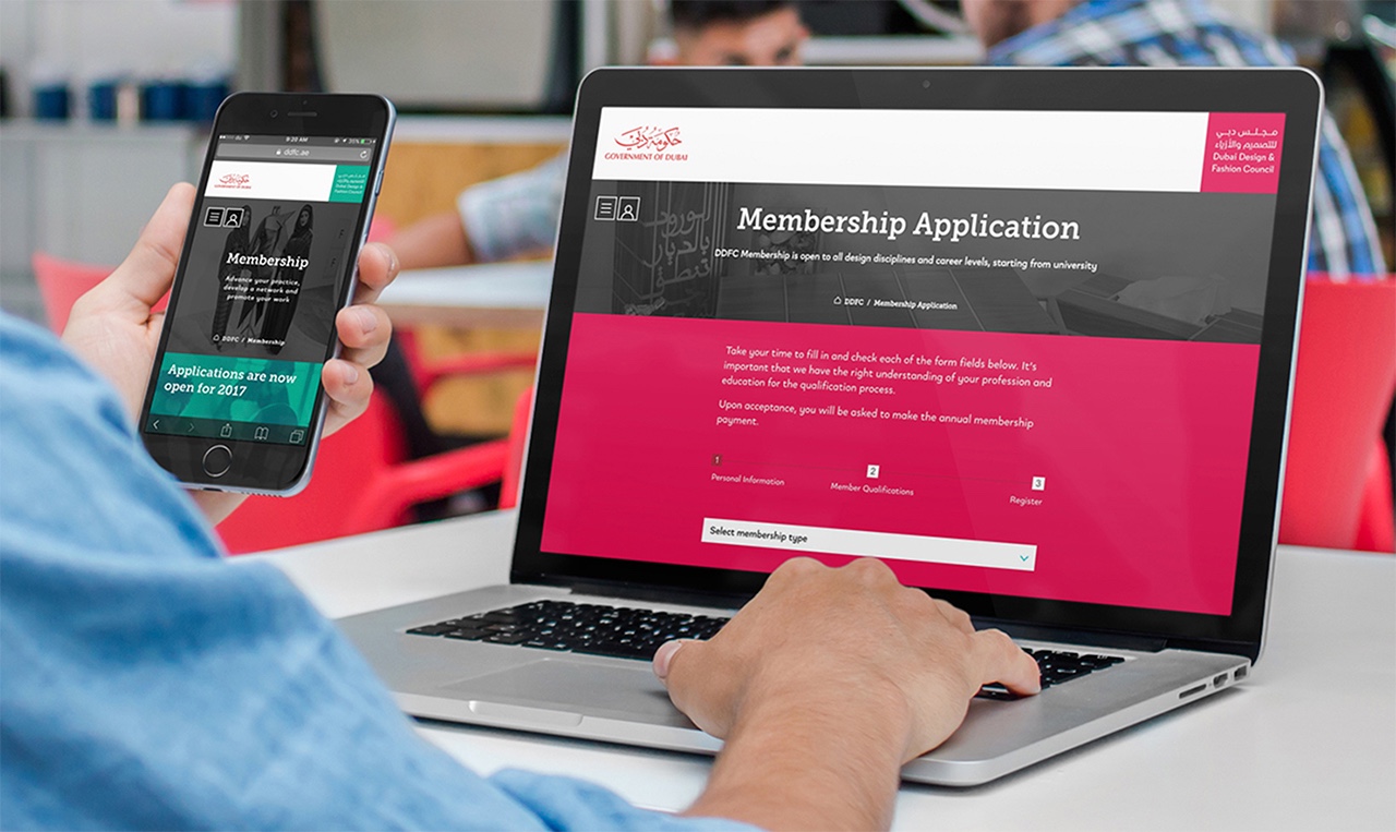 A man is using a laptop with a cell phone on it.