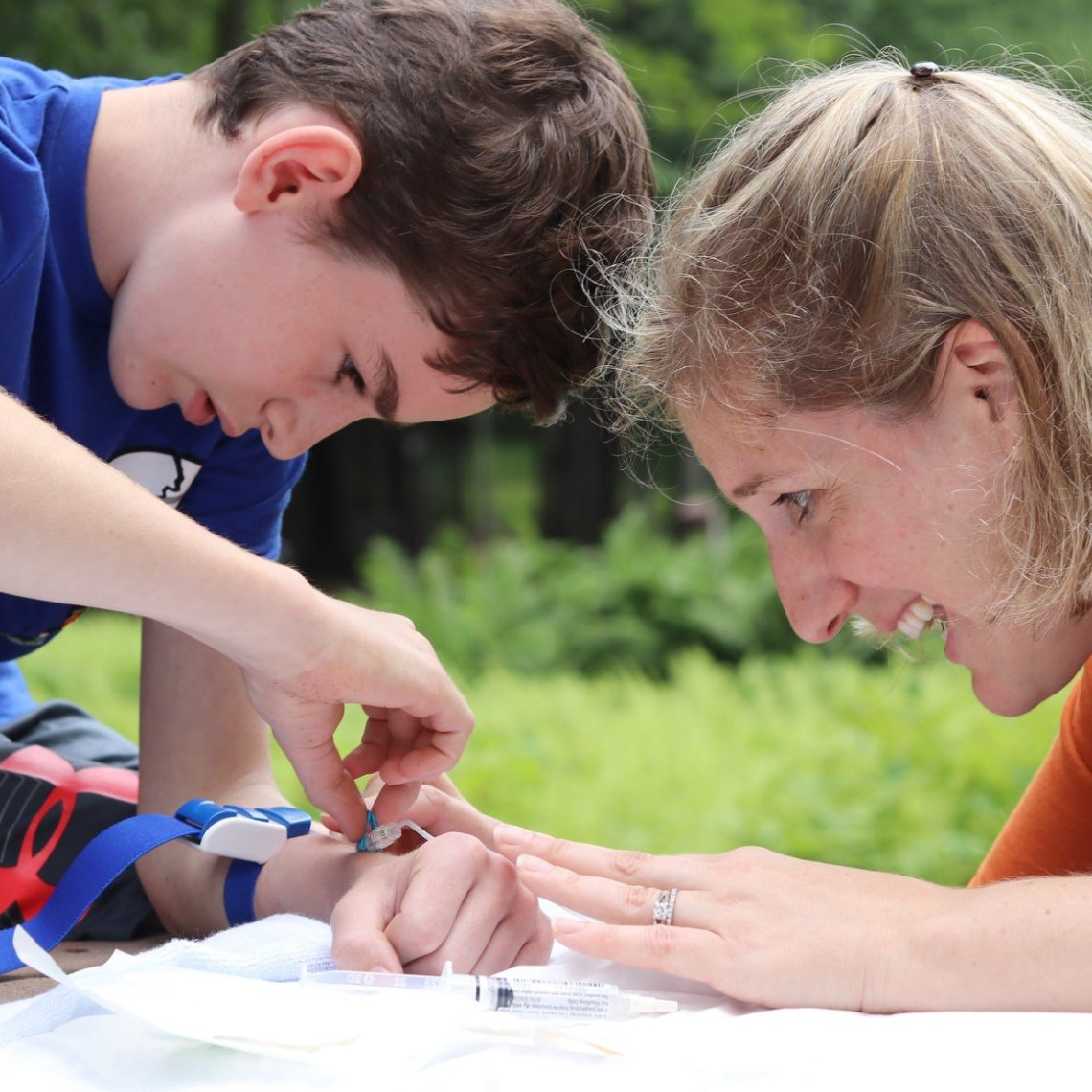 a young woman teaches a young man how to insert a catheter
