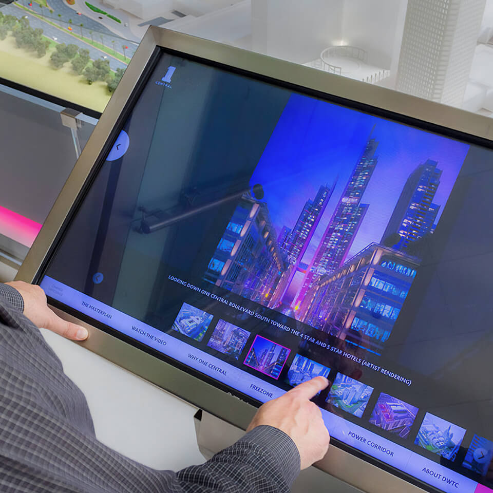 a person pointing at a touch screen showing the presentation developed for One Central