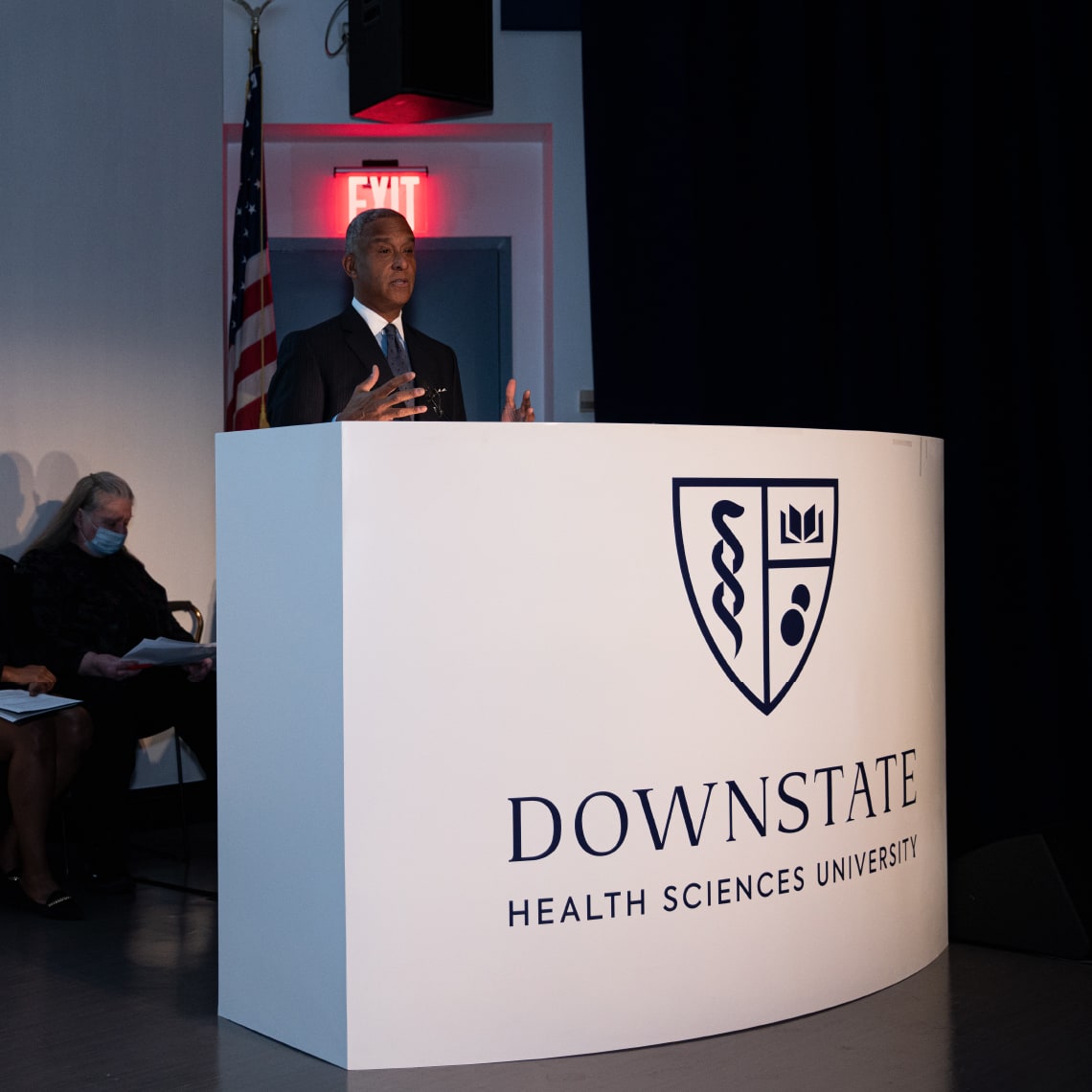 A man standing at a podium with the new SUNY brand identity applied