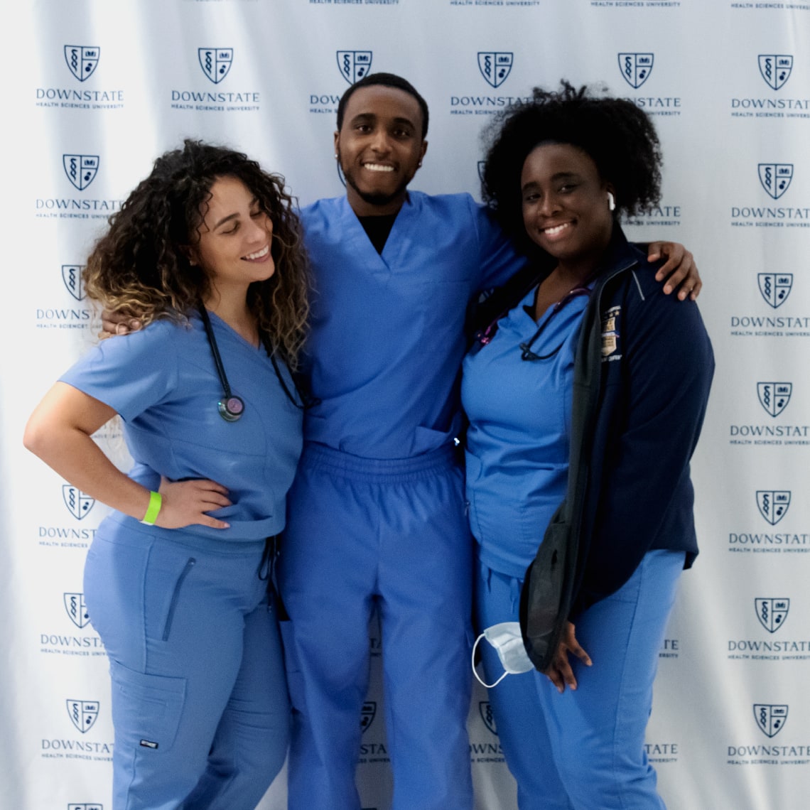 A group of three medical professionals standing next to each other on a wall with the sunny logo as a pattern.