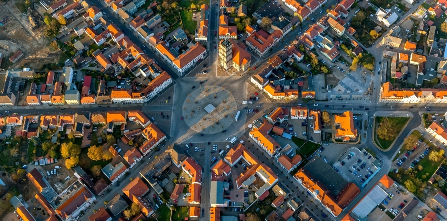 an aerial view of a city with many buildings, in the center a roundabout, with the geometry that inspired the logo
