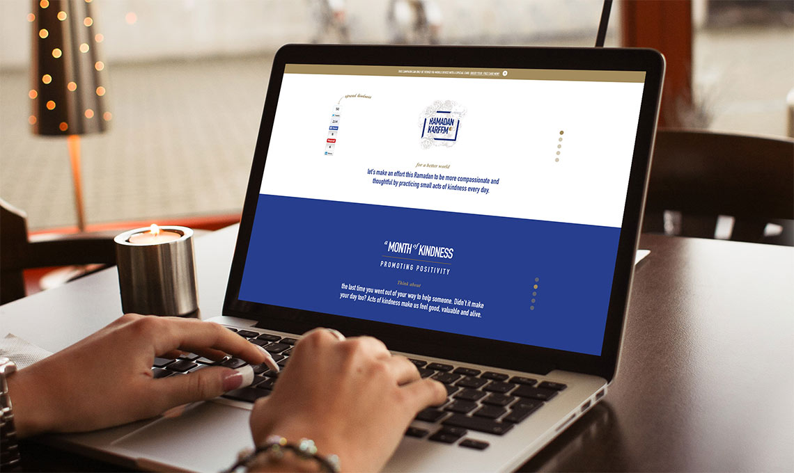 A person using a laptop on a table while sending a Ramadan greeting.