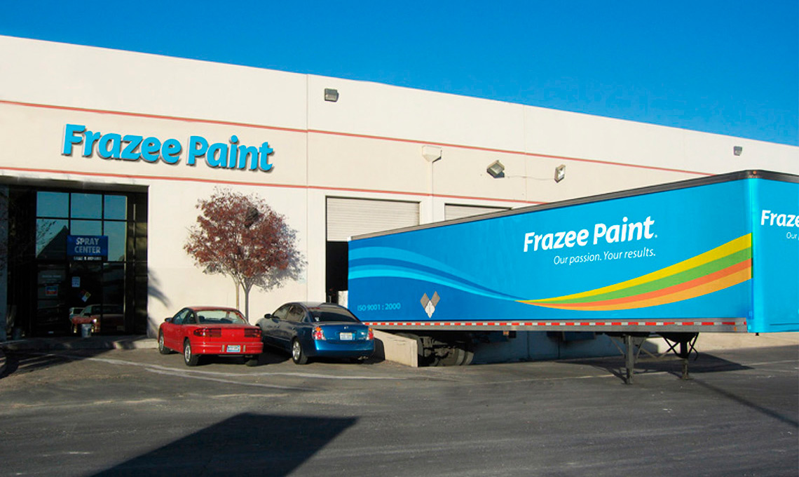 a large blue truck with the brand's identity applied parked in front of a building with the logo