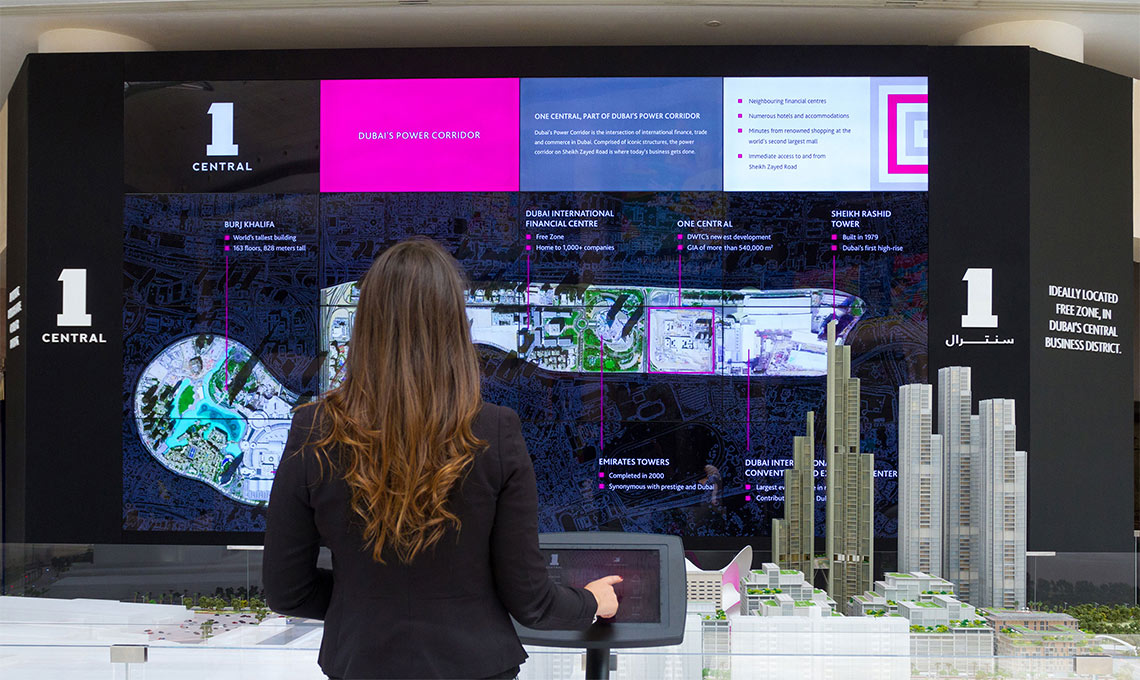 a woman in front a multimedia wall controlled by touchscreen device