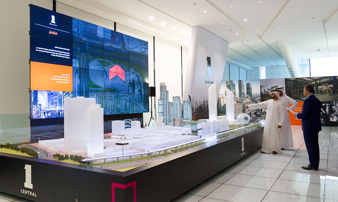 Three men looking at the model of the city and the Multimedia Wall designed for One Central
