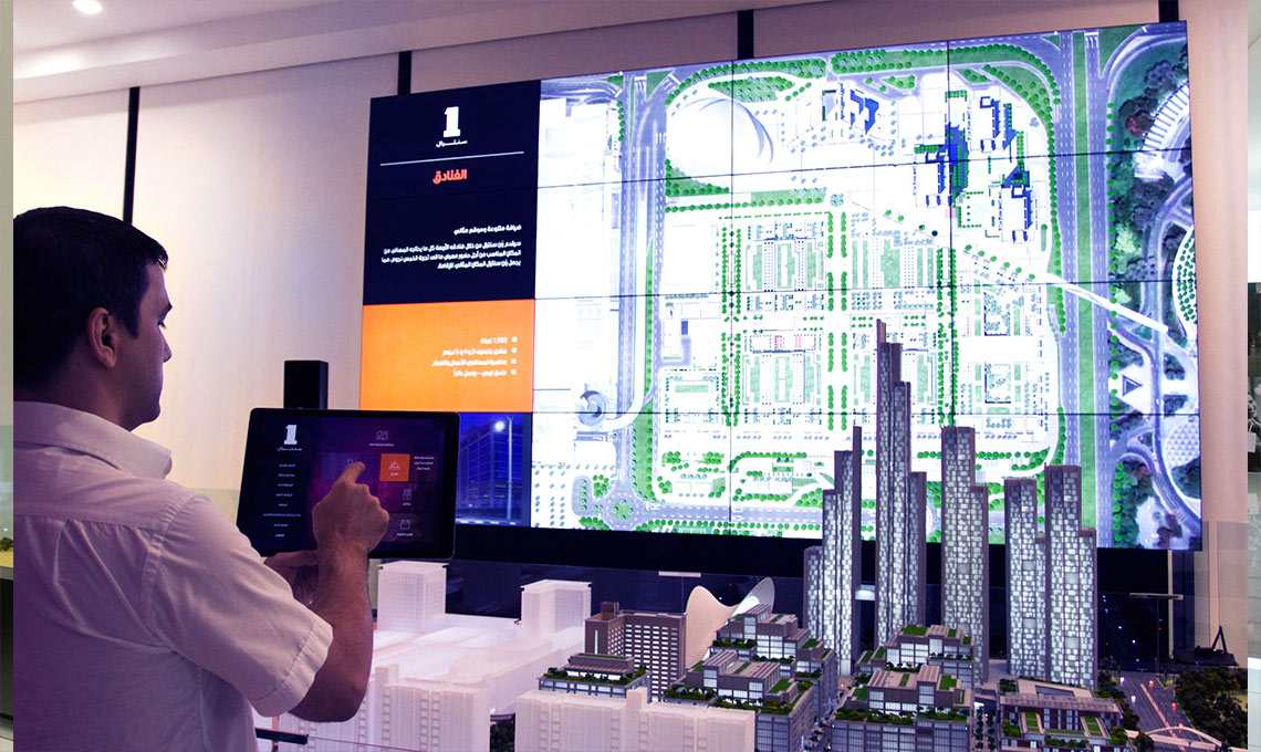 a person pointing at a touch screen showing the presentation developed for One Central