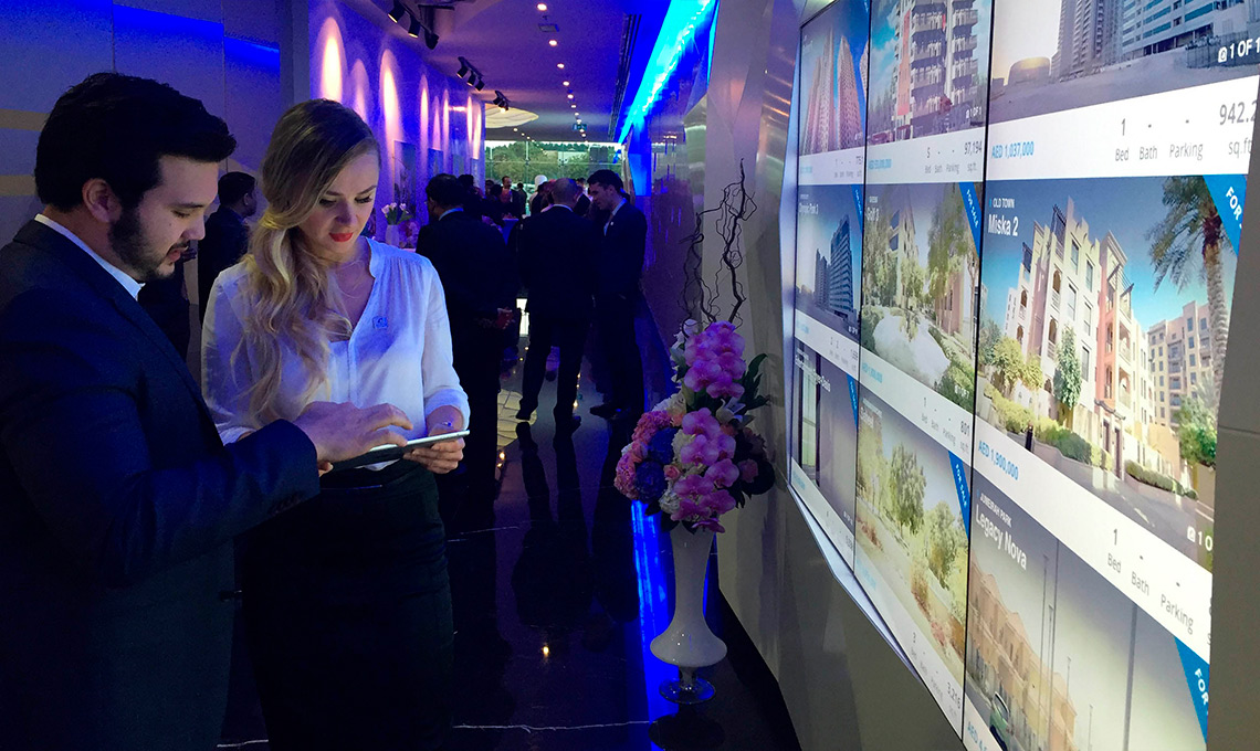 A man and a woman looking at a display of real estate on a corporate website.