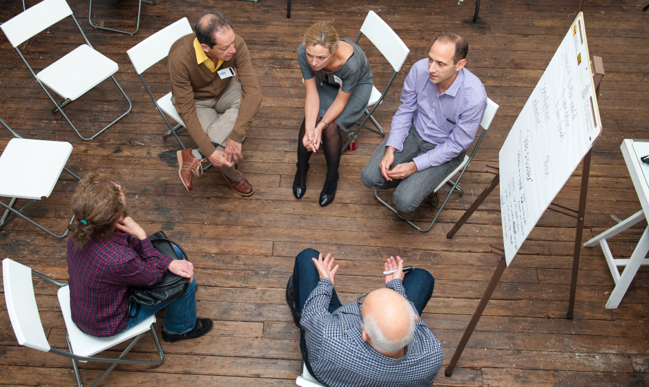 A group of people practicing user experience sitting around a table in a circle.
