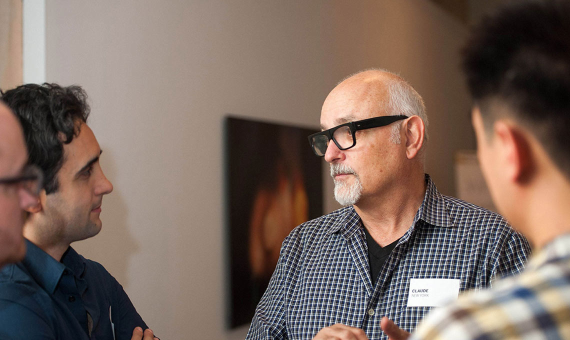 A group of men using a mobile app in an art gallery.