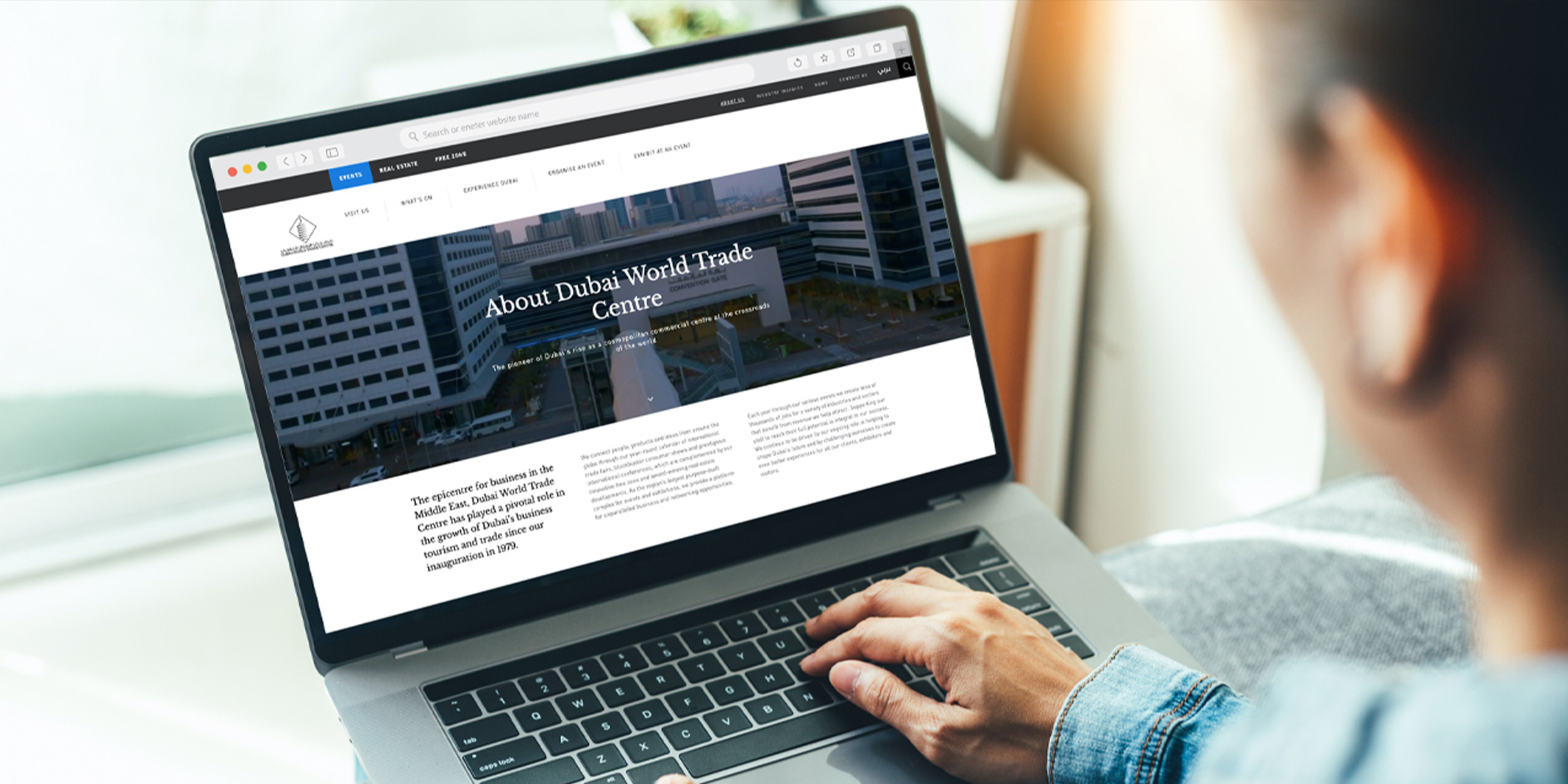 A businessperson using a Macbook to scroll through the DWTC website.