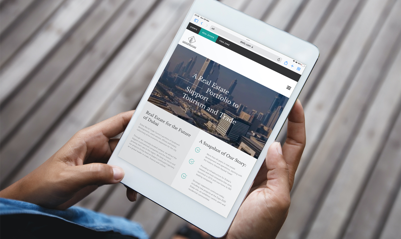 A businessman holding an iPad to scroll through a DWTC Real Estate landing page.