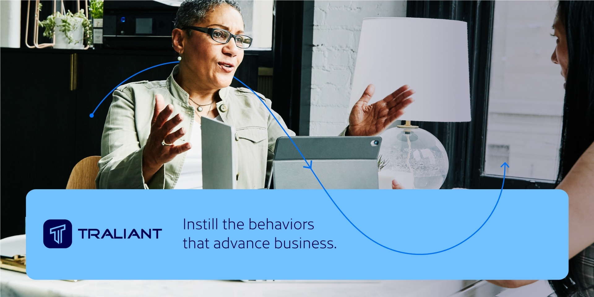 Example of the design system developed for Traliant: a photo of 2 woman in a business meeting with the headline: "Instill the behaviors that advance business."