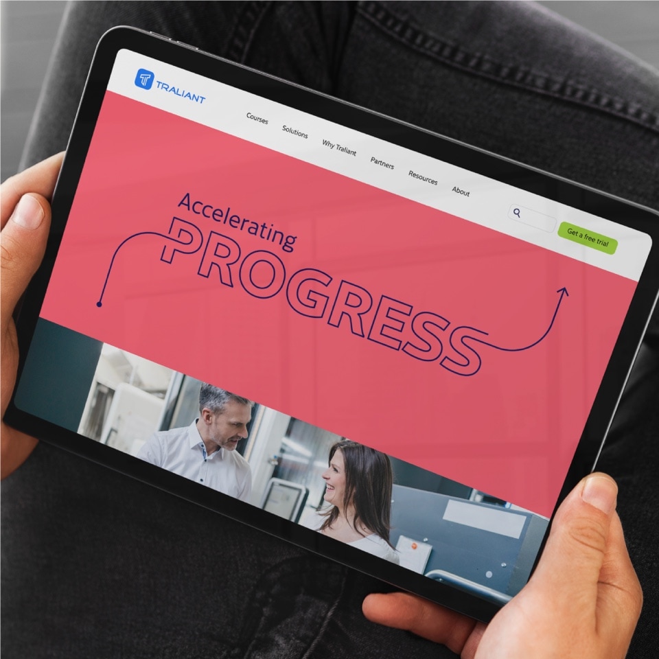 A man with a tablet in his hands with the website designed and developed for Traliant