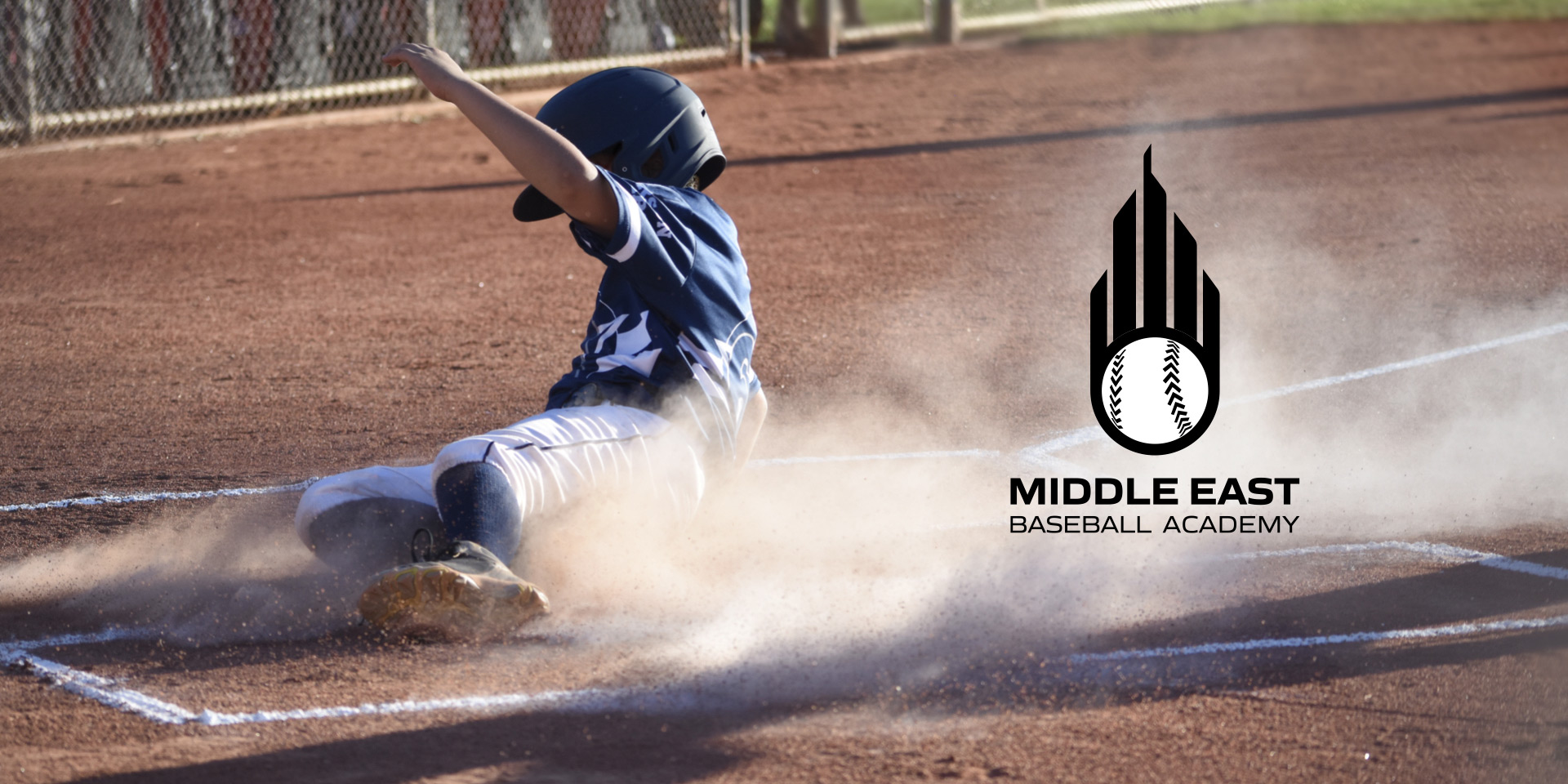 An action-packed shot of a child on the baseball diamond with sand rising from his fall.