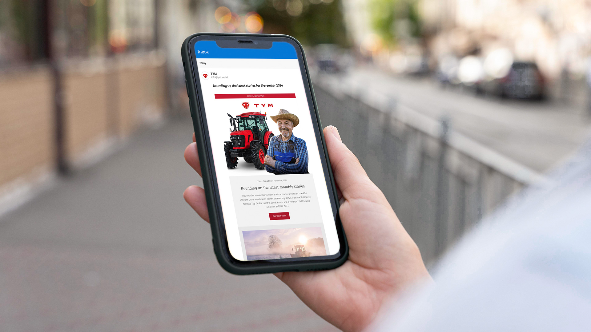A person holding and watching TYM’s monthly newsletter designed by OMNRAE through mobile device.