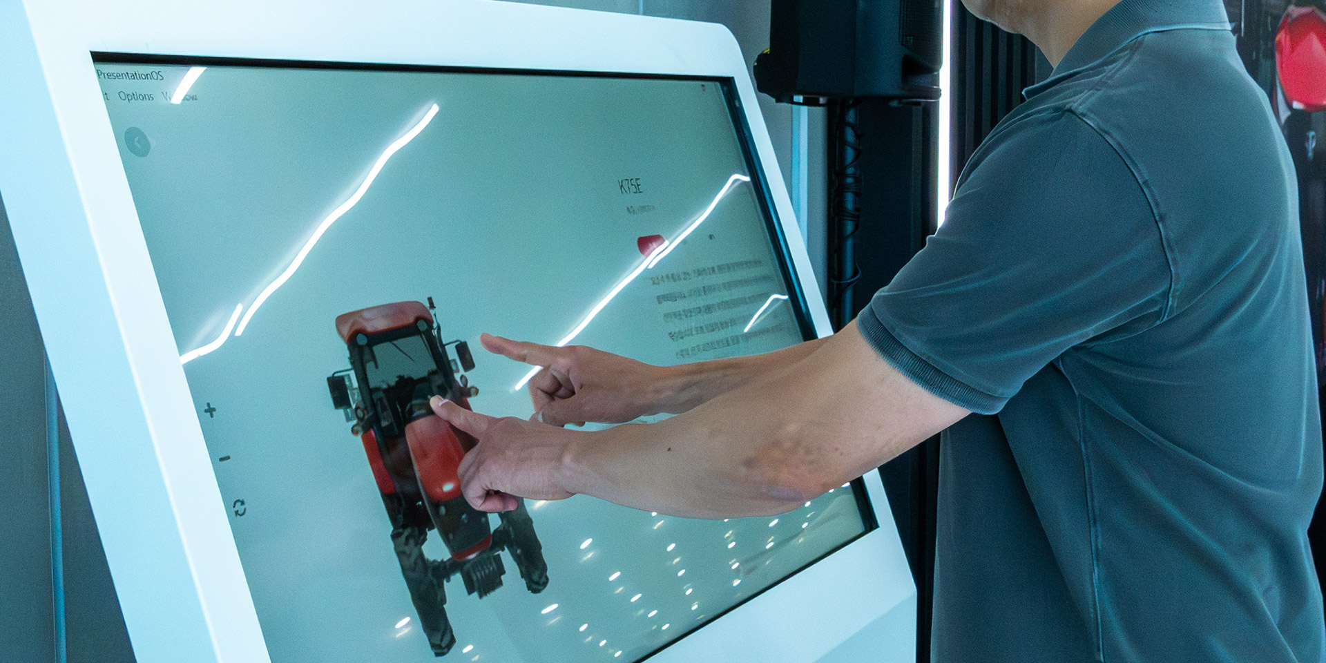A man interacts with the TYM tractor, using his fingers to see the tractor’s 360 degree view and description via the tool PresentationOS.