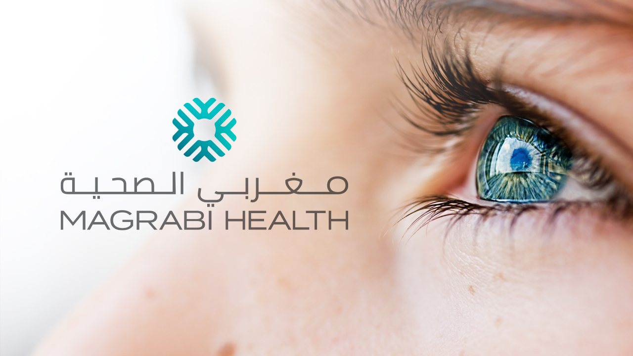 The Magrabi health logo with the watermark symbol, designed by OMNRAE over a close up image of a person’s eye honoring the brand’s ophthalmology legacy.