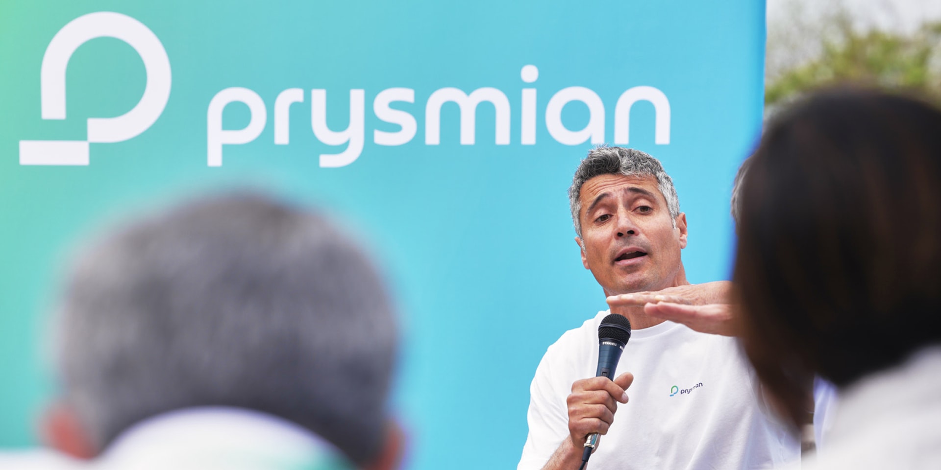 Giancarlo Pedote speaking to an audience in front of a backdrop displaying Prysmian's logo