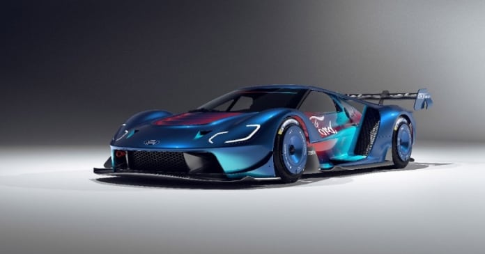 A blue and teal race car with aerodynamic design, large rear wing, and racing decals is displayed in a well-lit studio setting.